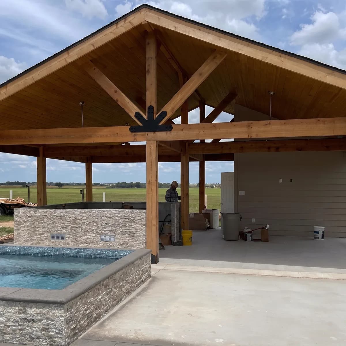 A 30 by 25 foot gabled cedar patio cover with tongue and groove ceiling built over a stone spa in Rockwall