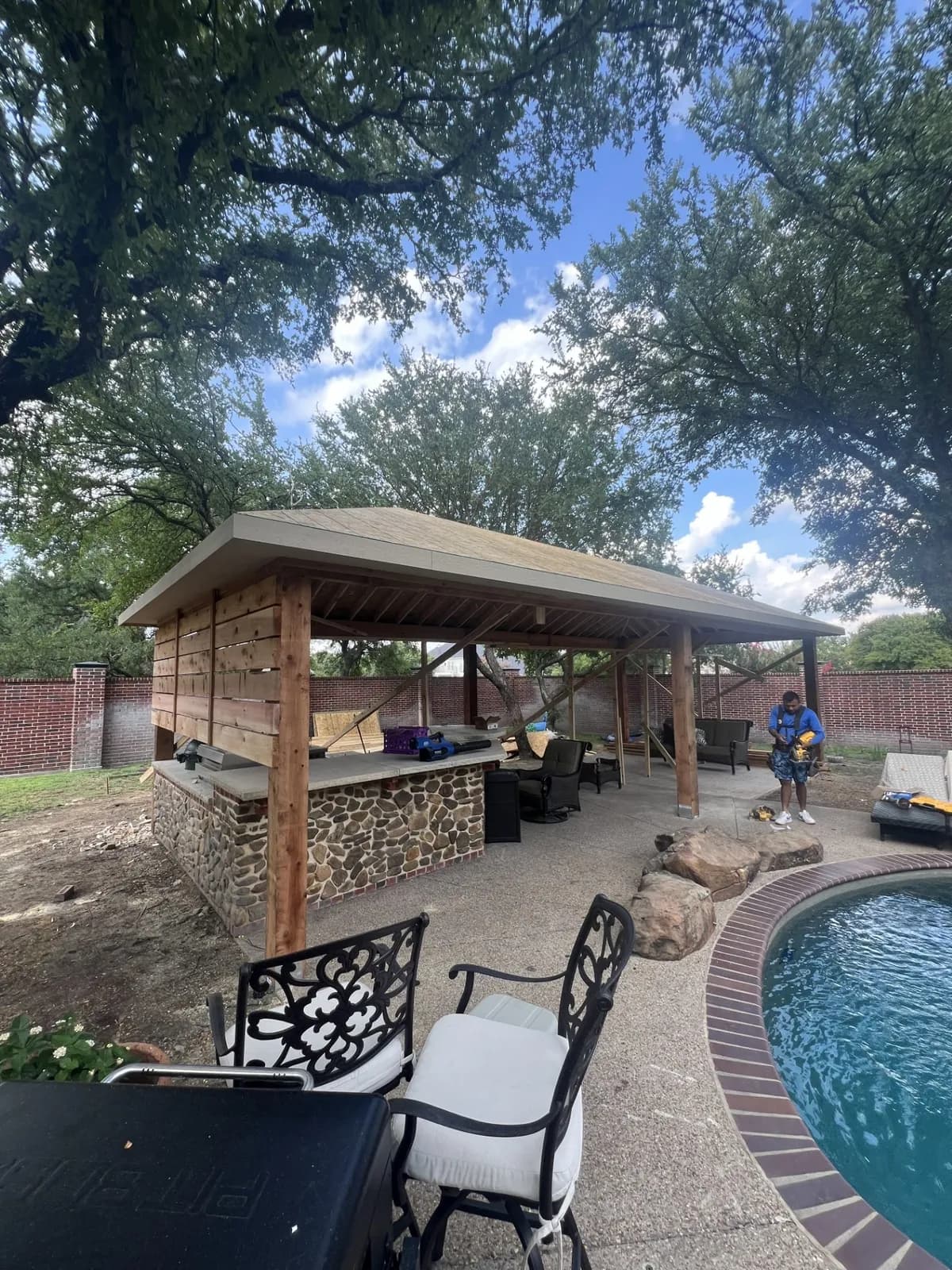 A Royal Patio cedar gable pavilion with an outdoor kitchen beside a pool