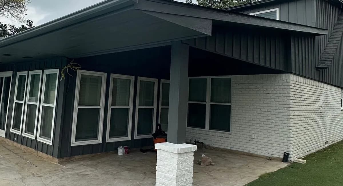A finished corner of a modern Royal Patio cover against painted brick