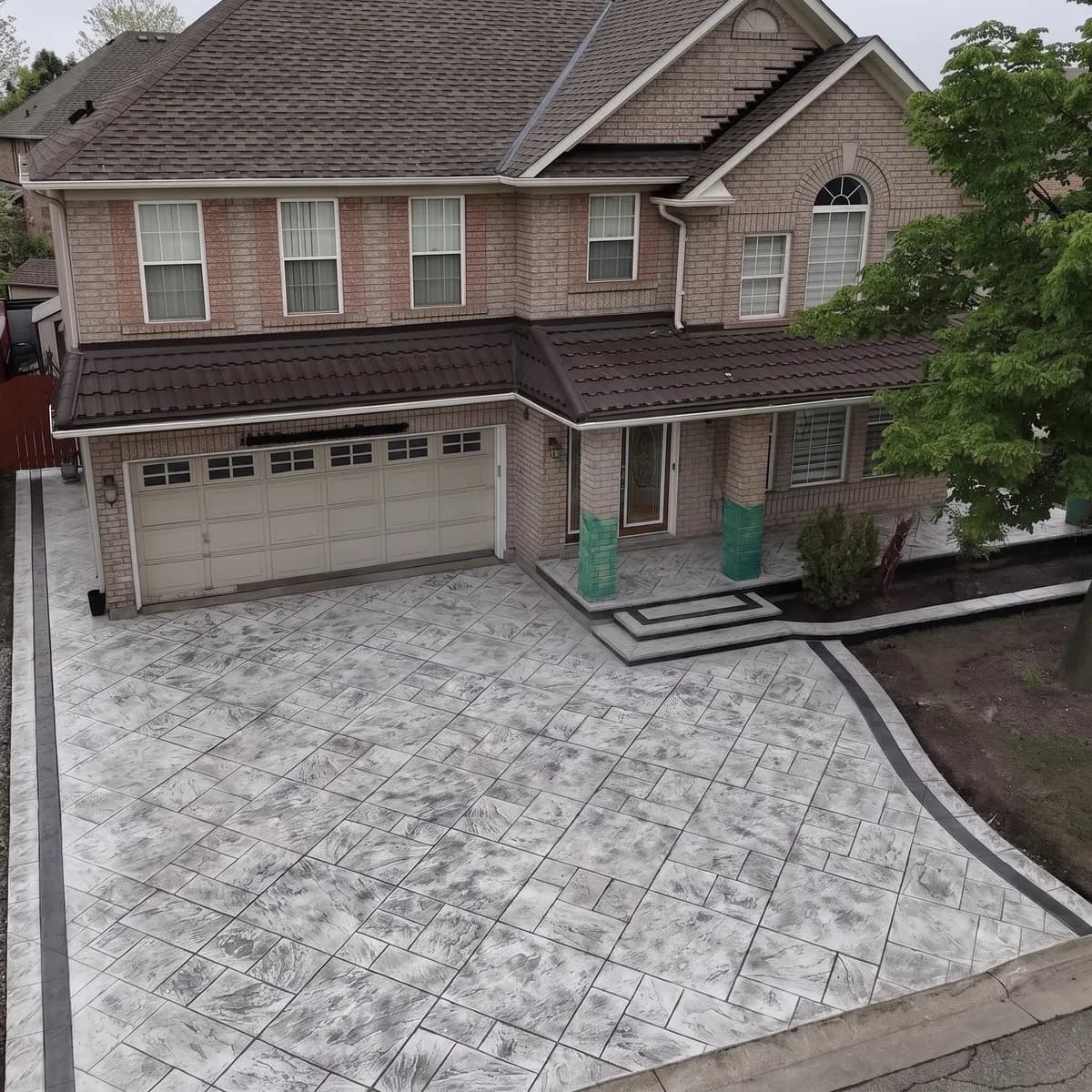 Aerial view of a stamped stone-pattern concrete driveway with a dark contrasting border