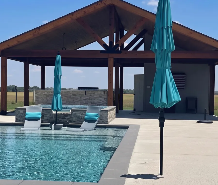 Gabled patio cover beside a pool with teal umbrellas